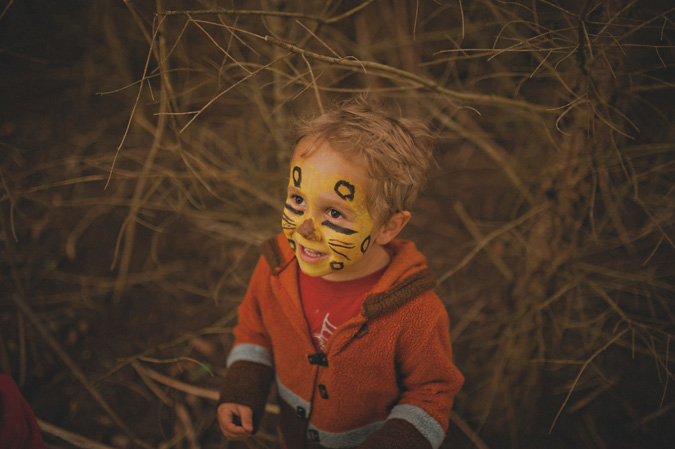 smiling child with face paint amongst the trees