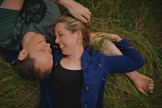couple lying in the long grass in an open field in comox, bc